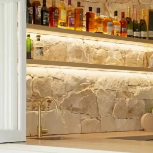 Entertainment kitchen area that seamlessly blends Sydney Sandstone, the warmth of American Oak, and brass drawer handles.