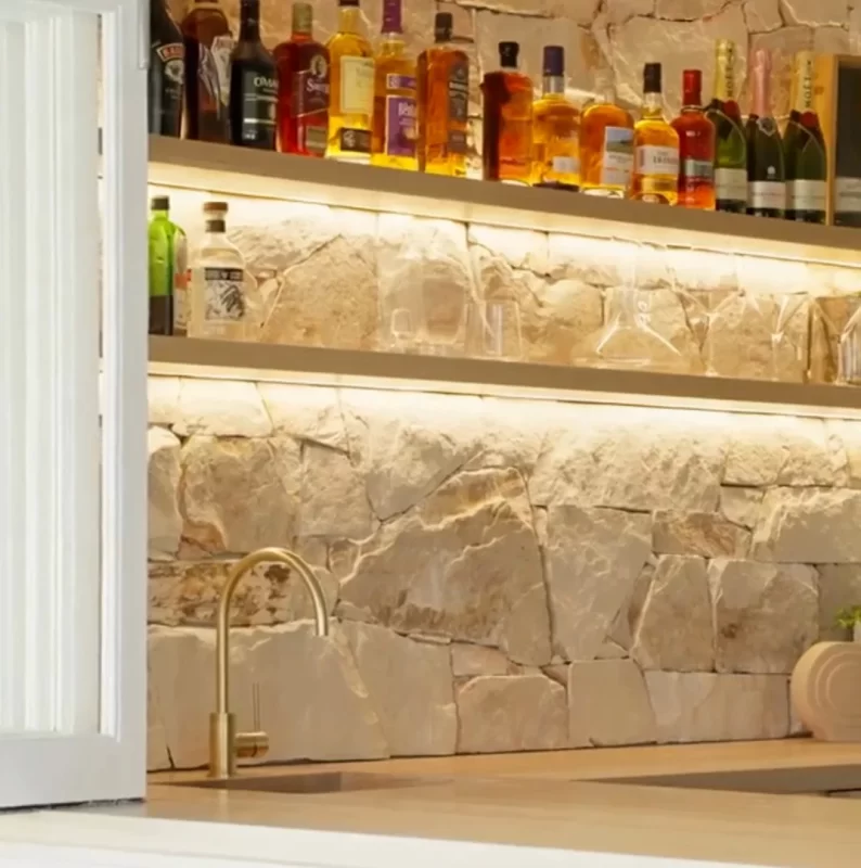 Entertainment kitchen area that seamlessly blends Sydney Sandstone, the warmth of American Oak, and brass drawer handles.